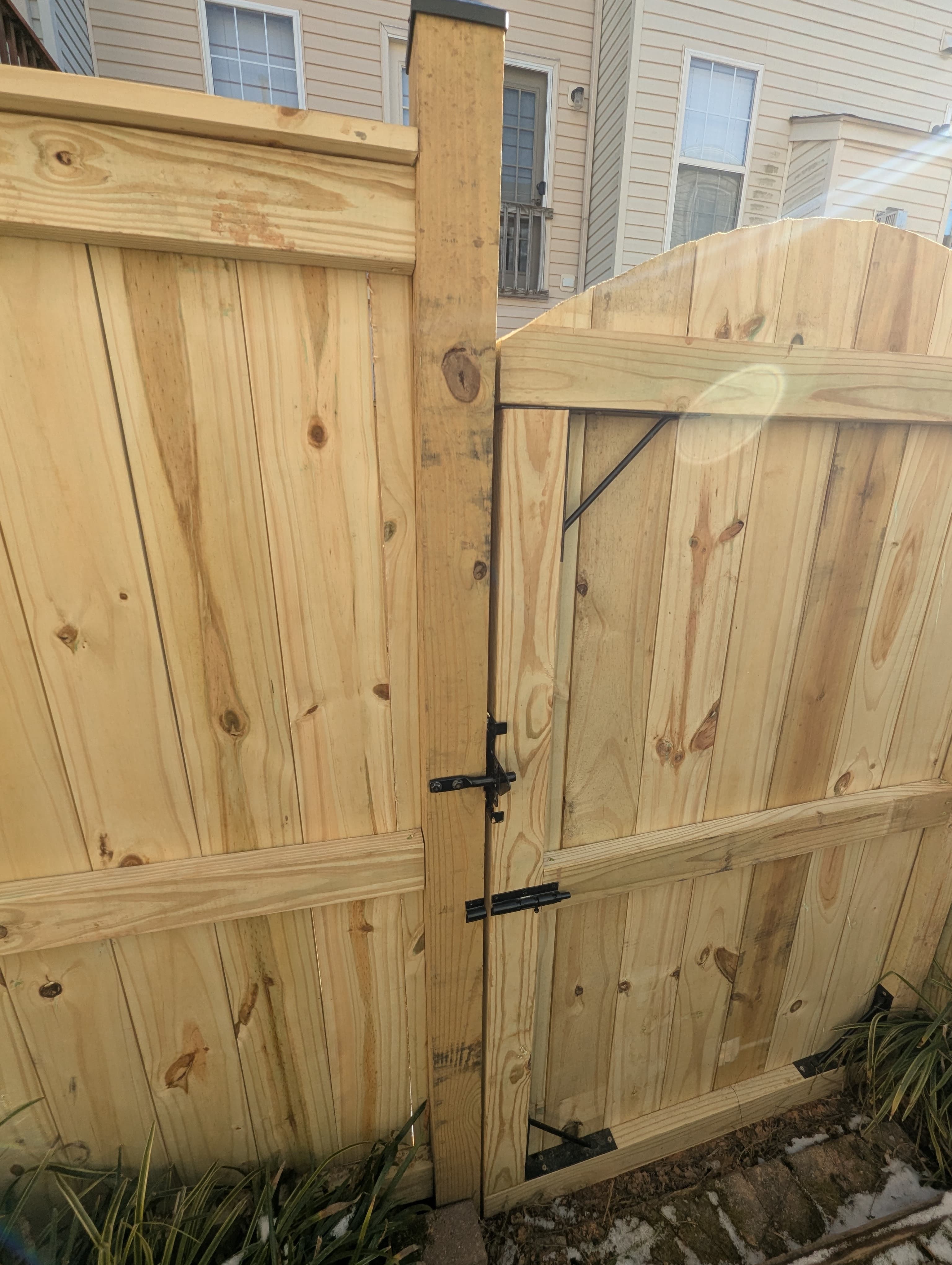 Close view of a wood privacy fence gate with latch and hinge hardware